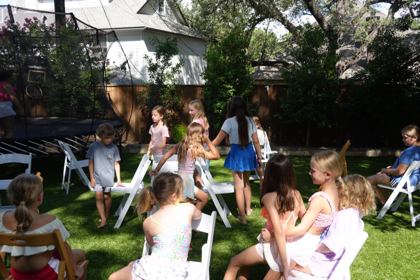 Campers circling folding chairs on the lawn in a game of musical chairs.