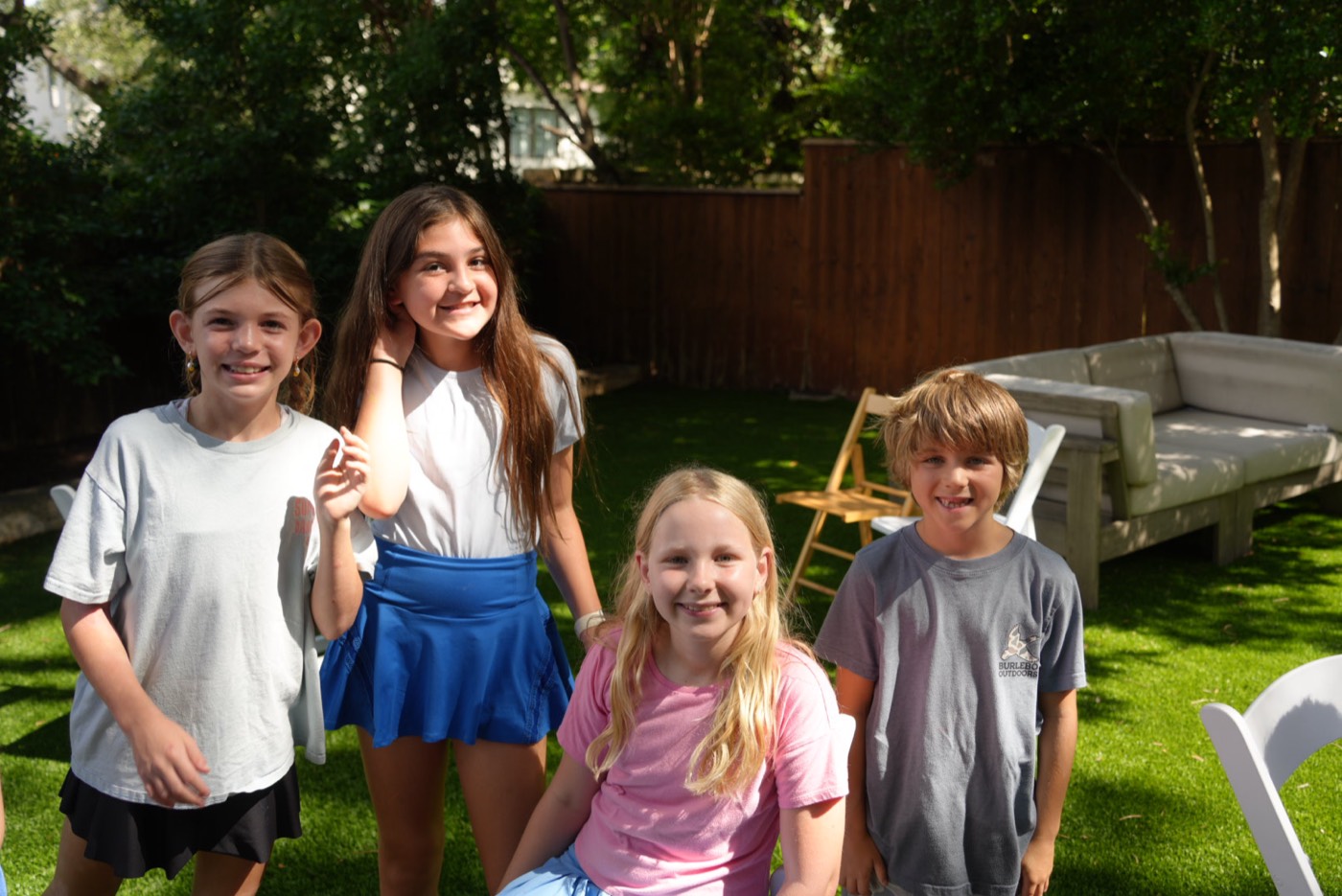 Four campers standing together on the lawn, smiling at the camera.